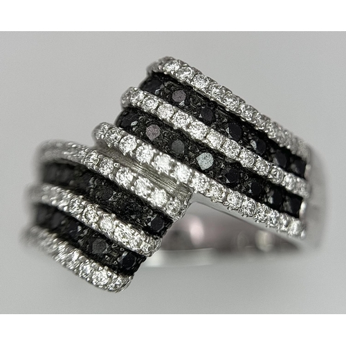 502 - A 14K WHITE GOLD WHITE & BLACK DIAMOND CROSSOVER RING. 1.25CT. 7.8G IN WEIGHT. SIZE N AND 1/2. Ref: ... 