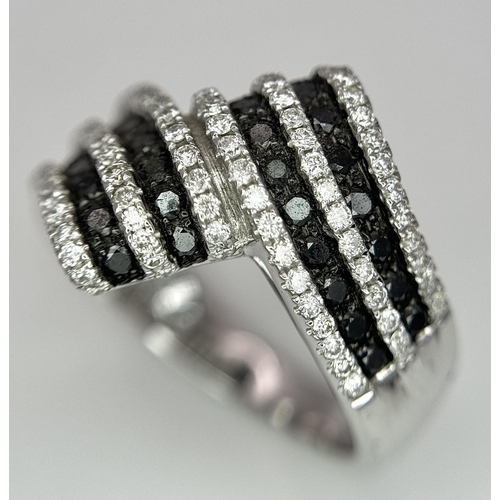 502 - A 14K WHITE GOLD WHITE & BLACK DIAMOND CROSSOVER RING. 1.25CT. 7.8G IN WEIGHT. SIZE N AND 1/2. Ref: ... 