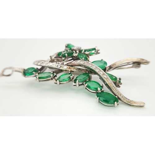 40 - An 18 K white gold brooch with a floral motif carrying oval and marquise cut emeralds  (5.5 carats a... 