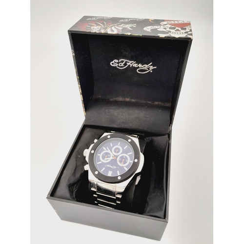 848 - An Ed Hardy Quartz Gents Watch. Stainless steel bracelet and case - 47mm. Still with tag. In case.