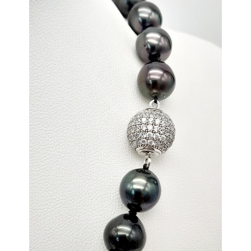 834 - A dark grey pearl necklace, graduating 10-13 mm natural spherical pearls with a glamorous diamante c... 