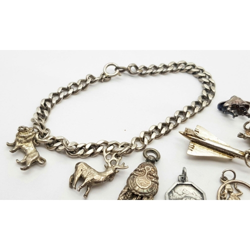 892 - A sterling silver chain bracelet and a total of fifteen charms including a post box, a teddy bear, a... 