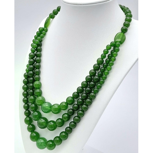 975 - A Chinese Three Row Graduating Green Jade Bead Necklace. Largest beads -14mm. 44-46cm