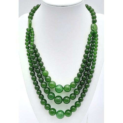 975 - A Chinese Three Row Graduating Green Jade Bead Necklace. Largest beads -14mm. 44-46cm