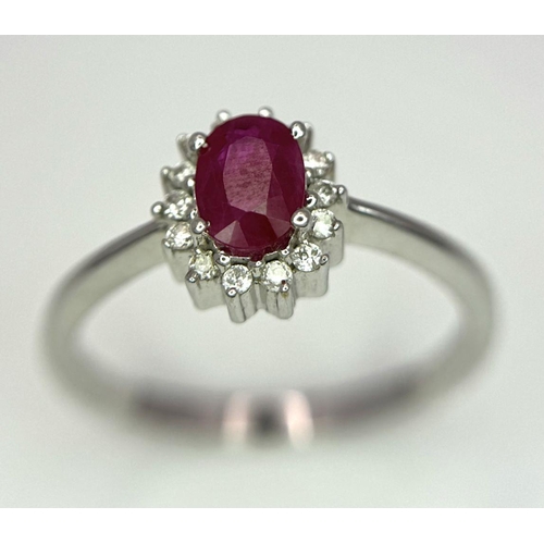 996 - An 18K White Gold Ruby and Diamond Ring. Central oval cut ruby with a diamond halo. Size N. 2.7g tot... 