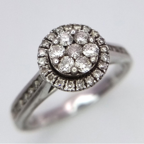 940 - A 9K White Gold Diamond Cluster Ring. Decorative floral shape. Size N. 4g total weight.