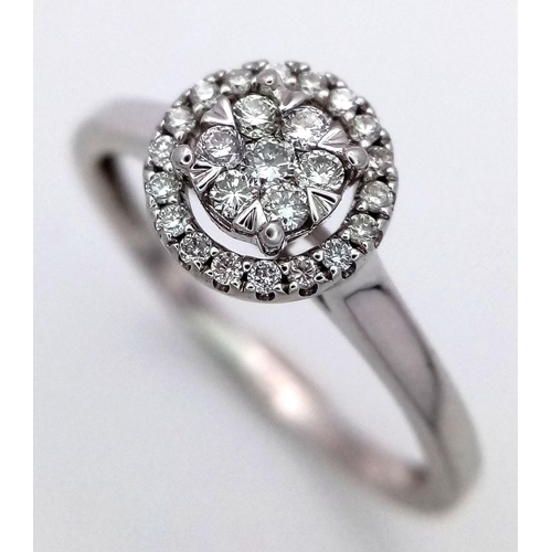 1072 - A 9K White Gold Diamond Cluster Ring. A circle of round cut diamonds with a halo of smaller round cu... 