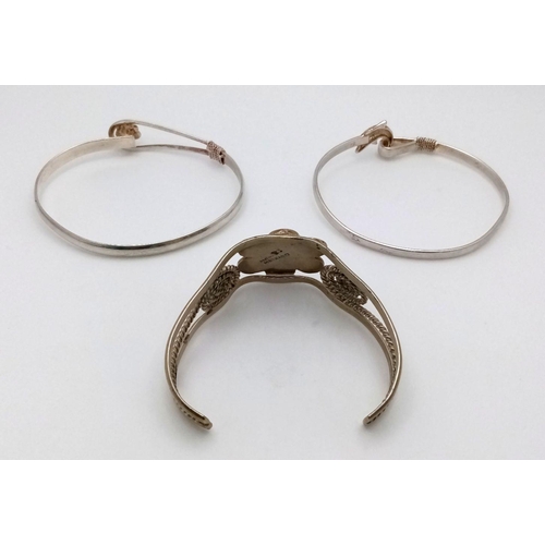 1097 - Three sterling silver bangles, one with MOP floral motif, one with a dolphin clasp and the third wit... 