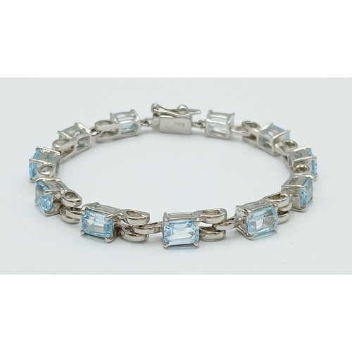 800 - A Rectangular Step Cut Blue Topaz Tennis Bracelet. On 925 silver. 28ctw. 18cm length, 17.4g total we... 