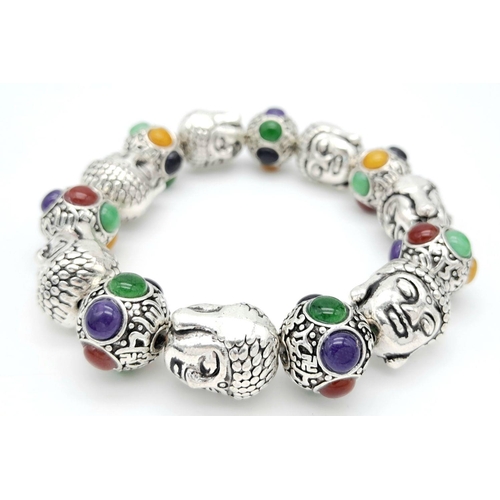 536 - A Tibetan Silver Buddha Head Expandable Bracelet. Multi-coloured jade cabochon decoration.