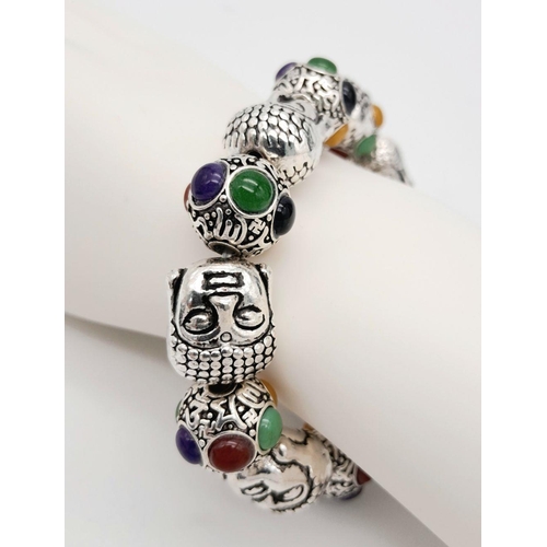 536 - A Tibetan Silver Buddha Head Expandable Bracelet. Multi-coloured jade cabochon decoration.