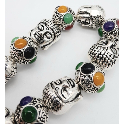 536 - A Tibetan Silver Buddha Head Expandable Bracelet. Multi-coloured jade cabochon decoration.