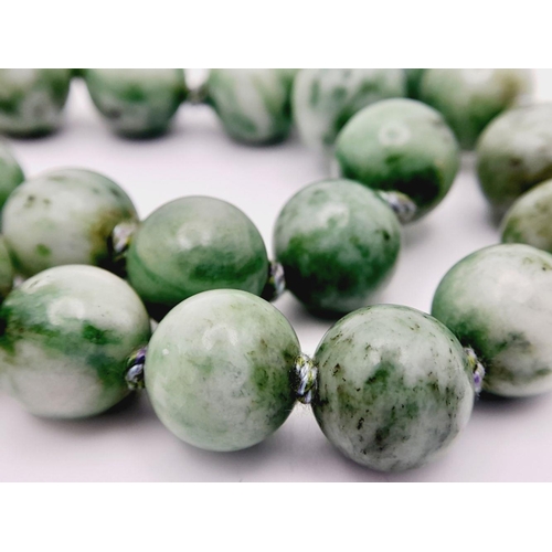 569 - An Antique Jade Necklace with Silver Clasp. 12mm diameter beads, 64.5cm length, 134g total weight.