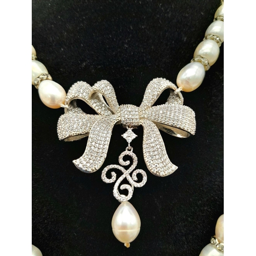 105 - A very glamorous two string cultured pearl necklace with a show stopping bow, loaded with cubic zirc... 