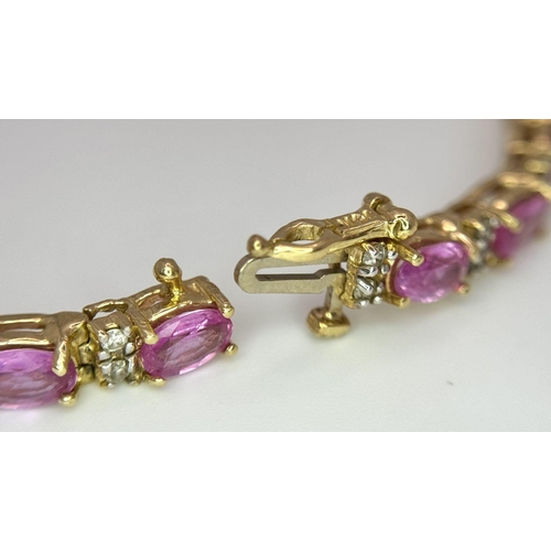 50 - A 14K Yellow Gold, Pink Sapphire and Diamond Tennis Bracelet. Oval cut sapphires with twin diamond s... 