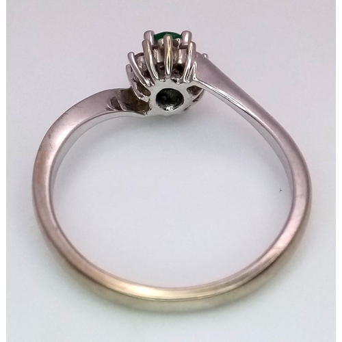 537 - A 18K WHITE GOLD 0.23CT DIAMOND & OVAL EMERALD CLUSTER TWIST RING. TOTAL WEIGHT 2.7G. SIZE M. REF ME... 