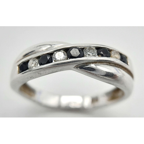 364 - 9 carat WHITE GOLD RING. Crossover Style set with SPINEL GEMSTONES. Full UK hallmark. 2 grams.  Size... 