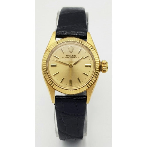 45 - A LADIES ROLEX OYSTER PERPETUAL IN 18K GOLD WITH THE ORIGINAL ROLEX BLACK LEATHER STRAP.    26mm