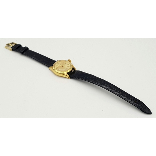 45 - A LADIES ROLEX OYSTER PERPETUAL IN 18K GOLD WITH THE ORIGINAL ROLEX BLACK LEATHER STRAP.    26mm