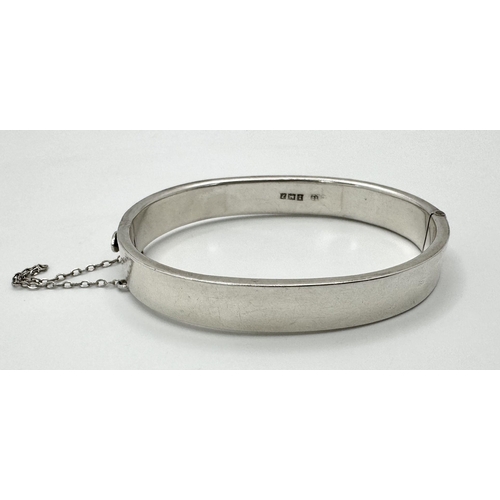 512 - A Sterling silver engraved bangle with bird motif and safety chain. 6.5cm wide, 16.1g in total weigh... 