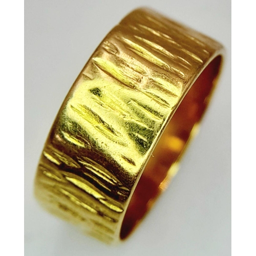 72 - AN 18K GOLD BAND RING WITH BARKED FINISH .    5.4gms    size K