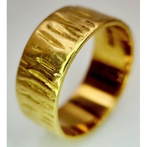 72 - AN 18K GOLD BAND RING WITH BARKED FINISH .    5.4gms    size K