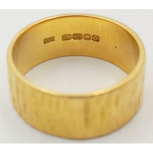 72 - AN 18K GOLD BAND RING WITH BARKED FINISH .    5.4gms    size K