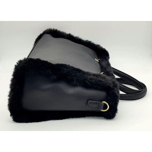 1518 - A Dune of London Handbag. Black textured exterior with gold tone hardware. Faux fur interior lining.... 