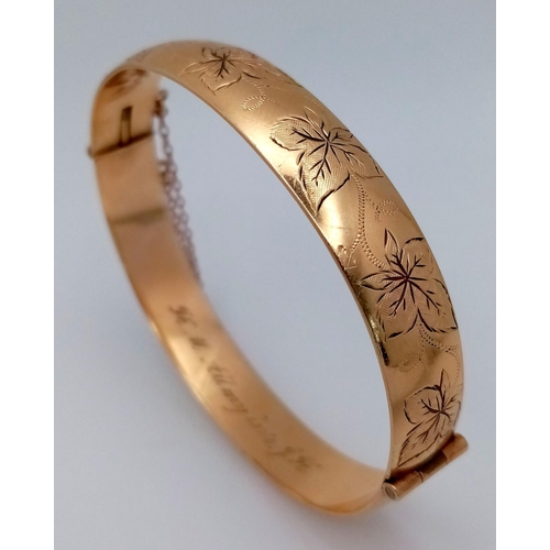 1511 - A stylish 9K yellow rolled gold bangle with floral motif engravings. Come with safety chain. Total w... 