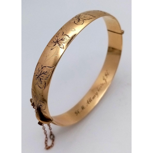 1511 - A stylish 9K yellow rolled gold bangle with floral motif engravings. Come with safety chain. Total w... 