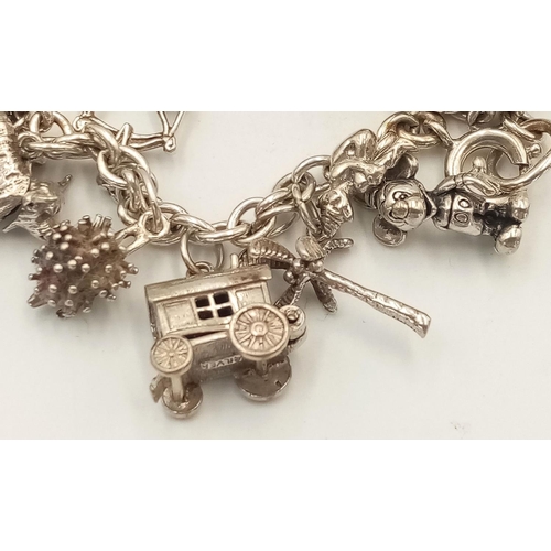 577 - A Sterling Silver Charm Bracelet with 22 Charms. 19cm Length. Gross Weight 53.3 Grams. Various Charm... 