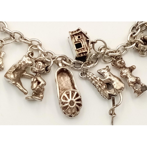 577 - A Sterling Silver Charm Bracelet with 22 Charms. 19cm Length. Gross Weight 53.3 Grams. Various Charm... 