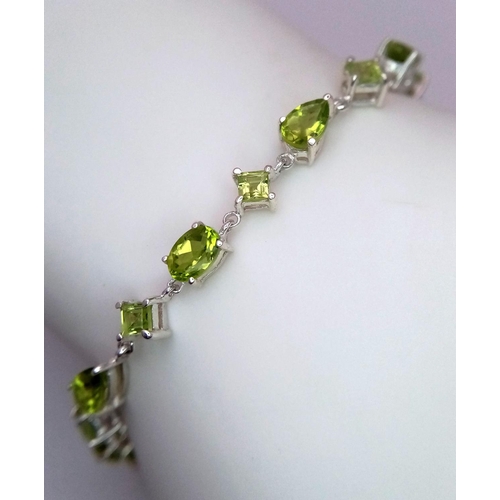 626 - A Sterling Silver, Various Cut, Peridot Set Tennis Bracelet. 18cm Length. Set with Pear, Square and ... 