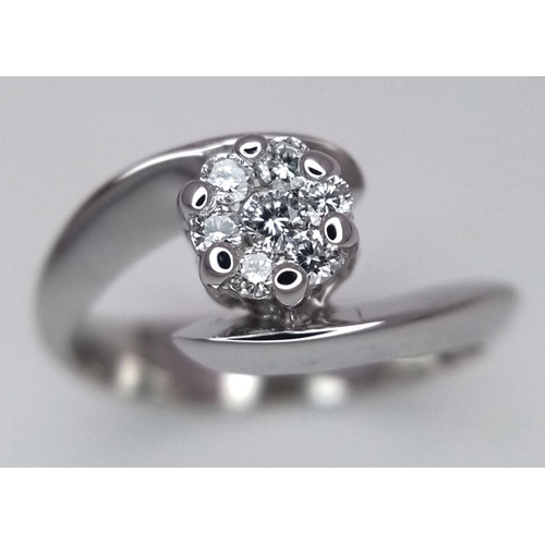 547 - An 18K White Gold and Diamond Crossover Ring. A seven diamond central cluster. Size O. 4.4g total we... 