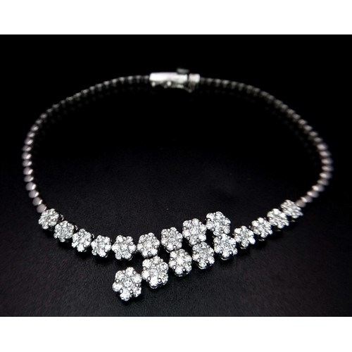 639 - An 18K White Gold and Diamond Bracelet. Graduating floral diamond cluster links that overlap. 1.5ctw... 