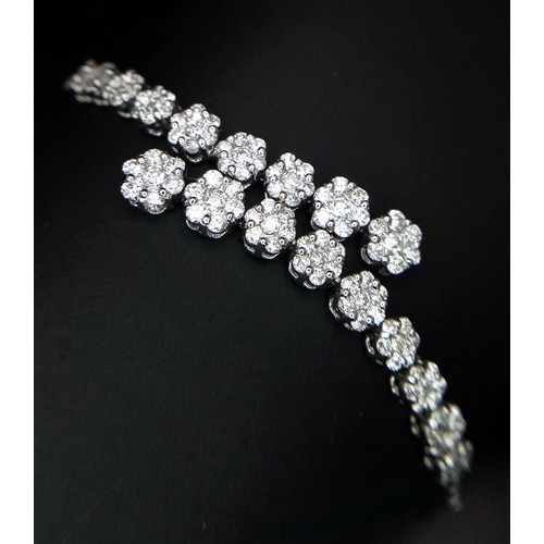 639 - An 18K White Gold and Diamond Bracelet. Graduating floral diamond cluster links that overlap. 1.5ctw... 