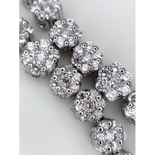 639 - An 18K White Gold and Diamond Bracelet. Graduating floral diamond cluster links that overlap. 1.5ctw... 