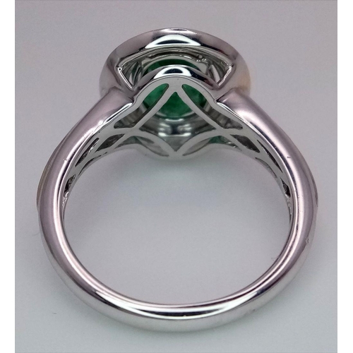 39 - An 18K White Gold, Emerald and Diamond Ring. A hypnotic 2ct oval cut central green emerald with a 0.... 