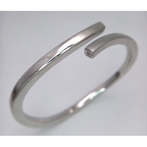 83 - A 9K WHITE GOLD CROSSOVER HINGED BANGLE - 12.7G. REF: JBA1