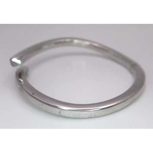 83 - A 9K WHITE GOLD CROSSOVER HINGED BANGLE - 12.7G. REF: JBA1