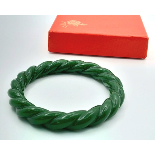 108 - A vintage, Chinese, hand carved, green jade bangle with an eternal twisted design, in its original p... 