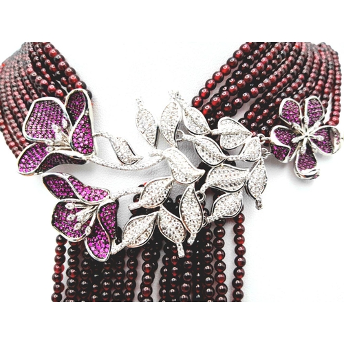 73 - A statement multi gem necklace consisting of eleven strands with a spectacular central floral pendan... 