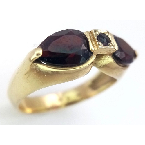 304 - AN 14K GOLD DESIGNER RING WITH UNUSUAL GARNET STONES  .            5.4gms    size Q