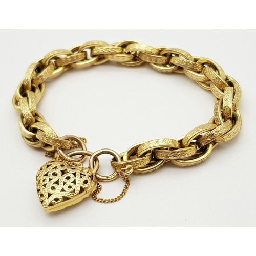 81 - A VINTAGE 9K GOLD HEAVY LINK BRACELT WITH EACH LINK BEING DECORATED AND HAVING AN ORNATE HEART PADLO... 