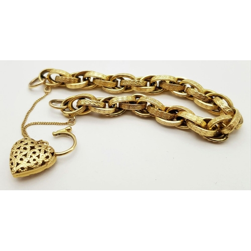 81 - A VINTAGE 9K GOLD HEAVY LINK BRACELT WITH EACH LINK BEING DECORATED AND HAVING AN ORNATE HEART PADLO... 