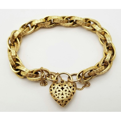 81 - A VINTAGE 9K GOLD HEAVY LINK BRACELT WITH EACH LINK BEING DECORATED AND HAVING AN ORNATE HEART PADLO... 