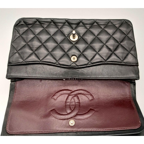 22 - A Chanel single flap crossbody bag in black lambskin leather. silver tone hardware, burgundy leather... 