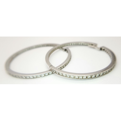 82 - A Pair of 18K White Gold and Diamond Large Hoop Earrings. 
Half-eternity round cut style. 4.5cm diam... 