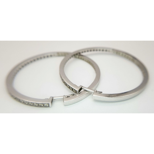 82 - A Pair of 18K White Gold and Diamond Large Hoop Earrings. 
Half-eternity round cut style. 4.5cm diam... 