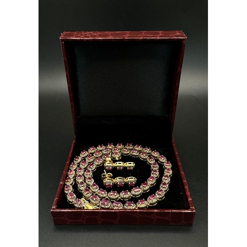 163 - A Ruby and Diamond Tennis Necklace and Drop Earrings Set. Oval cut deep red rubies each with an old ... 